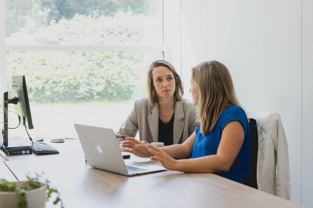 Two persons sitting behind a laptop and discussing an e-learning.